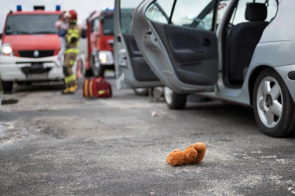 Accidente de tráfico en el que los servicios de emergencia sostienen a un niño