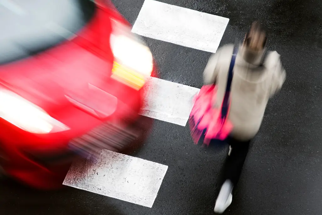 woman walking in crosswalk with blurred car