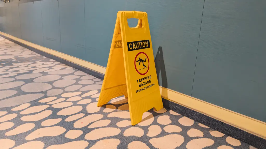 Señal amarilla de precaución por riesgo de tropiezo sobre la alfombra